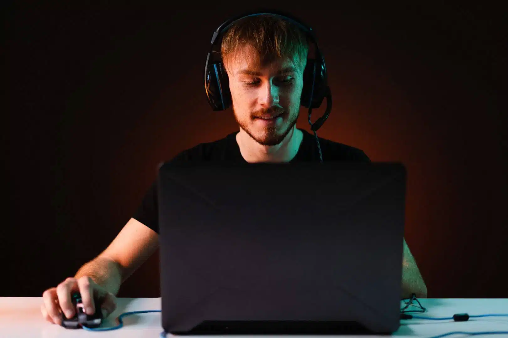 Gracz siedzący w słuchawkach przed laptopem gamingowym